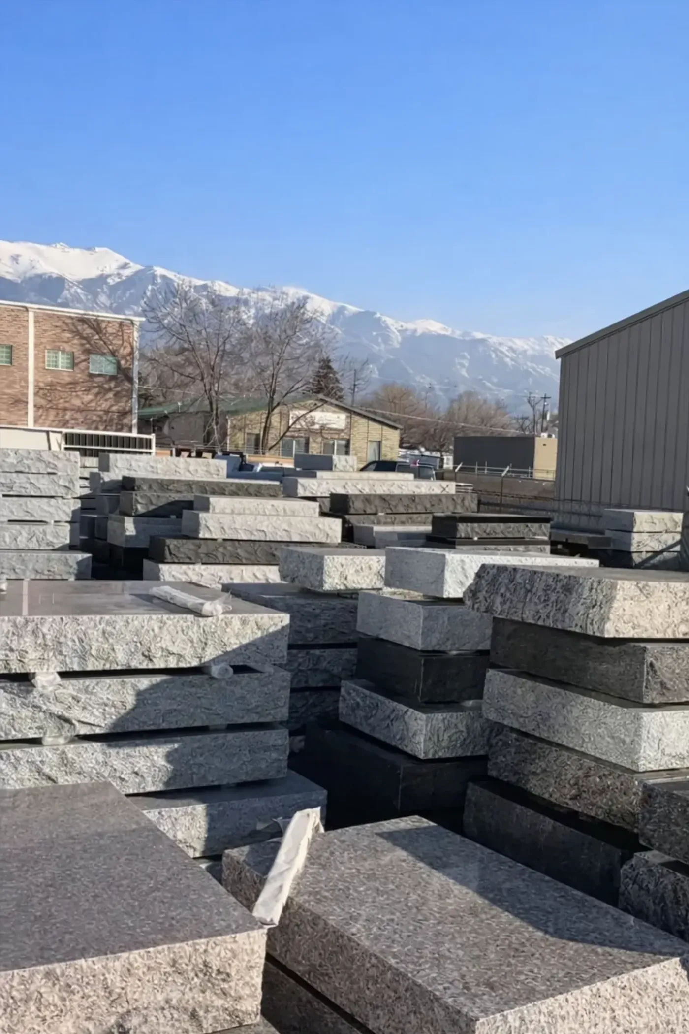 Premium granite slabs in the Utah Headstone Design yard with the Wasatch Mountains behind